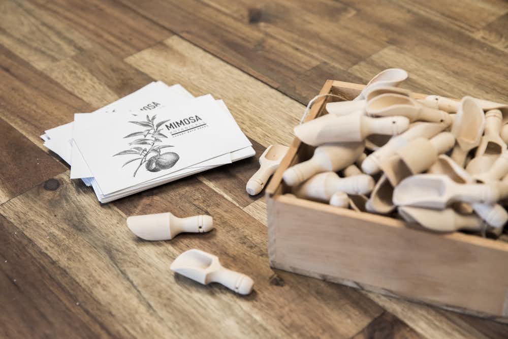 Mimosa Botanticals business card and small wooden serving spoons.